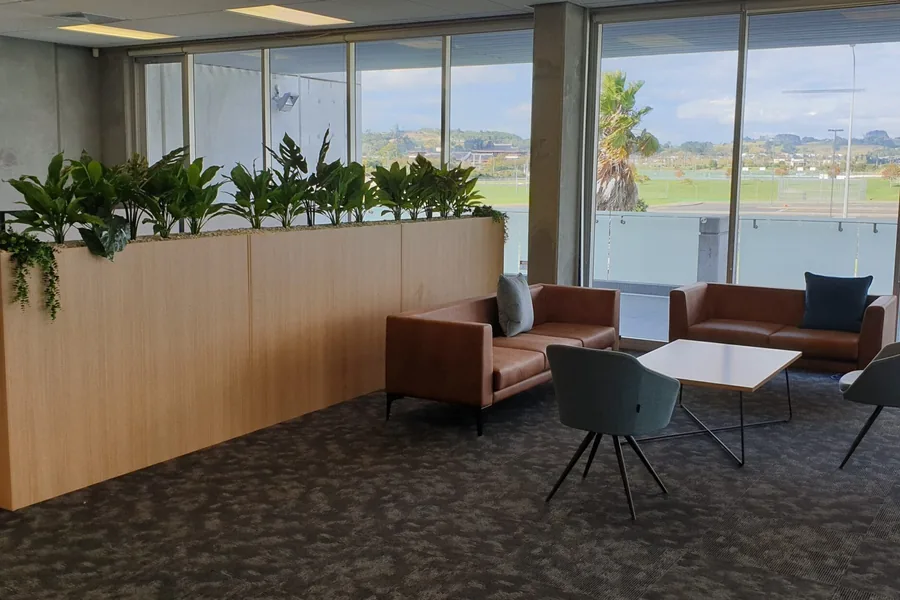 A timber-lined breakout area with planting and lounge seating at Jun Yue Investments